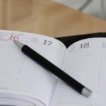 Agenda papier ouvert avec un stylo noir posé au centre, sur un bureau en lumière naturelle. Cette image symbolise l’accompagnement sur mesure d’Orizya Voyages, fondé sur la disponibilité humaine, la préparation minutieuse et la relation de confiance dans le temps.