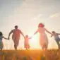 Famille courant dans un champ au coucher du soleil, symbole de liberté et d’évasion en famille. - voyager en famille