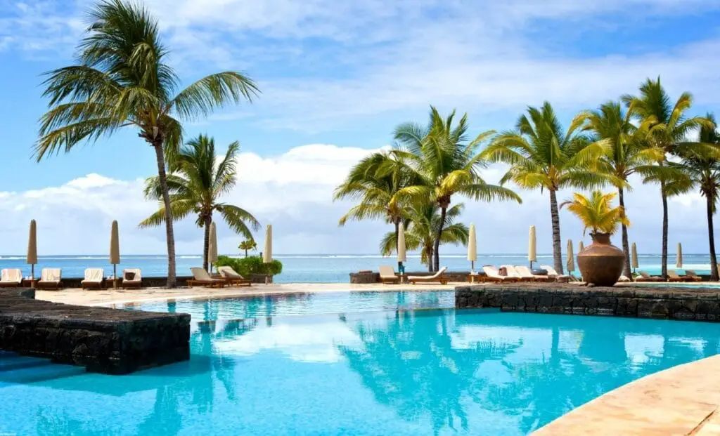 Piscine d’un hôtel de luxe face au lagon à l’île Maurice, entourée de palmiers sous un ciel ensoleillé - quand partir ile Maurice - Ile Maurice avec bébé