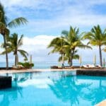 Piscine d’un hôtel de luxe face au lagon à l’île Maurice, entourée de palmiers sous un ciel ensoleillé - quand partir ile Maurice - Ile Maurice avec bébé