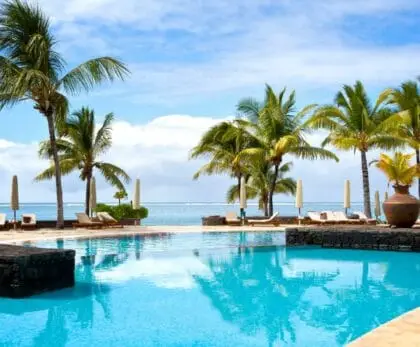 Piscine d’un hôtel de luxe face au lagon à l’île Maurice, entourée de palmiers sous un ciel ensoleillé - quand partir ile Maurice - Ile Maurice avec bébé