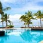 Piscine d’un hôtel de luxe face au lagon à l’île Maurice, entourée de palmiers sous un ciel ensoleillé - quand partir ile Maurice - Ile Maurice avec bébé
