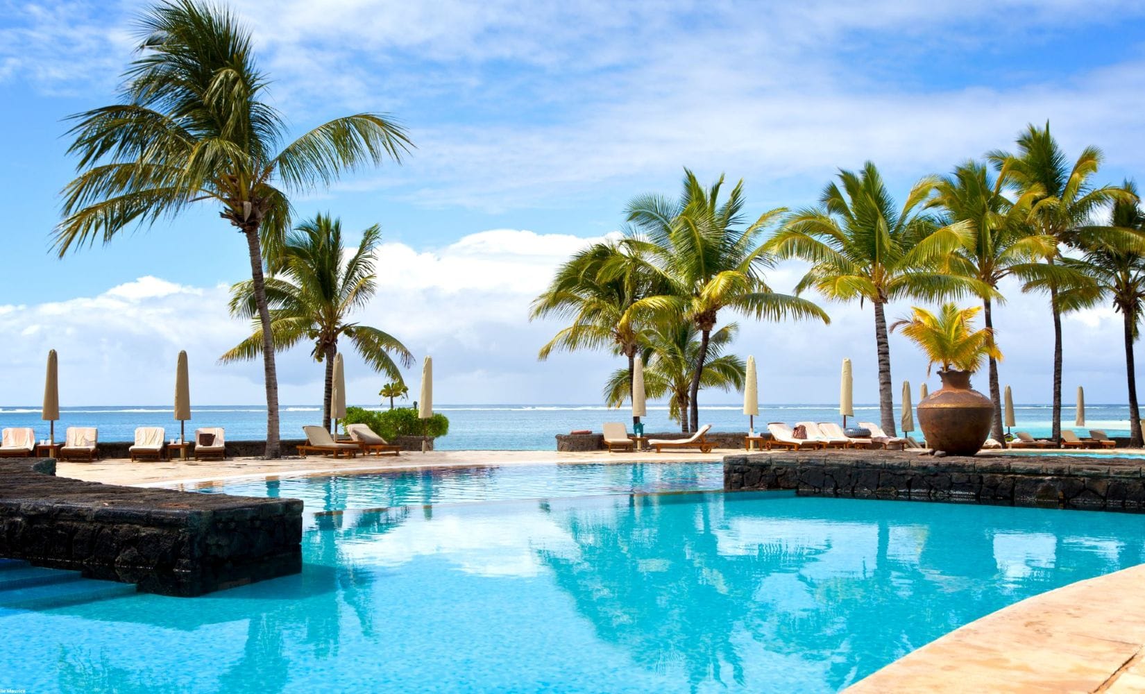 Piscine d’un hôtel de luxe face au lagon à l’île Maurice, entourée de palmiers sous un ciel ensoleillé - quand partir ile Maurice - Ile Maurice avec bébé