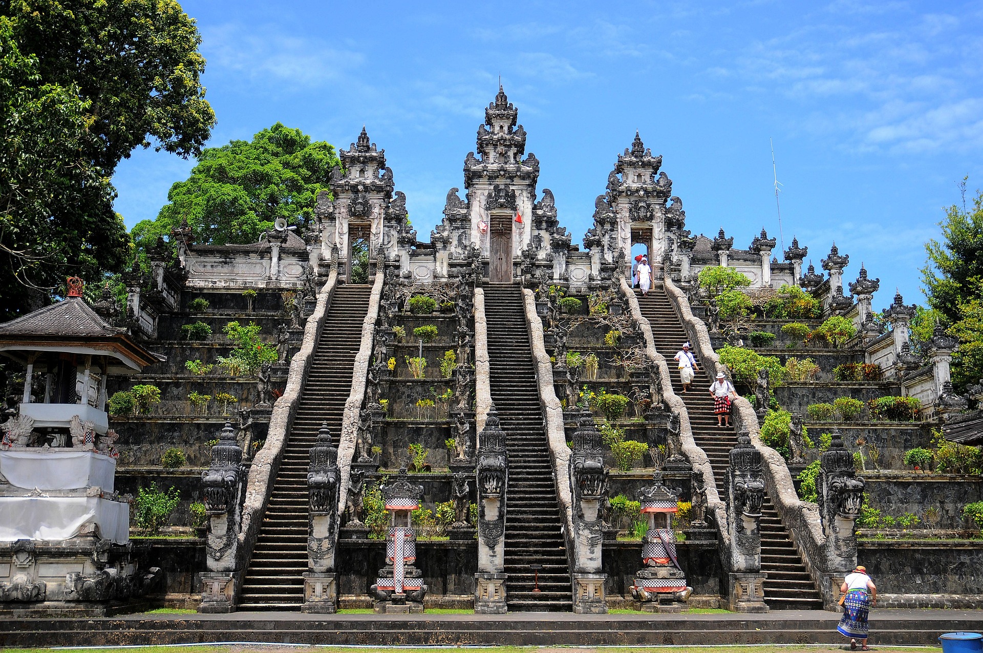 Escaliers monumentaux du temple Lempuyang à Bali, entourés de statues traditionnelles et de végétation luxuriante, sous un ciel bleu. - Voyage à Bali en famille