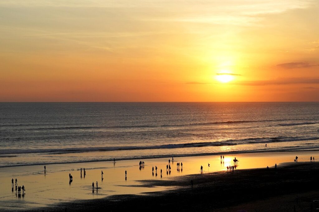 Plongez dans l’atmosphère unique de Seminyak au coucher du soleil : plage dorée, surfeurs à l’horizon et ambiance chic balinaise à deux pas des hôtels de luxe. - Meilleur Hôtel Bali