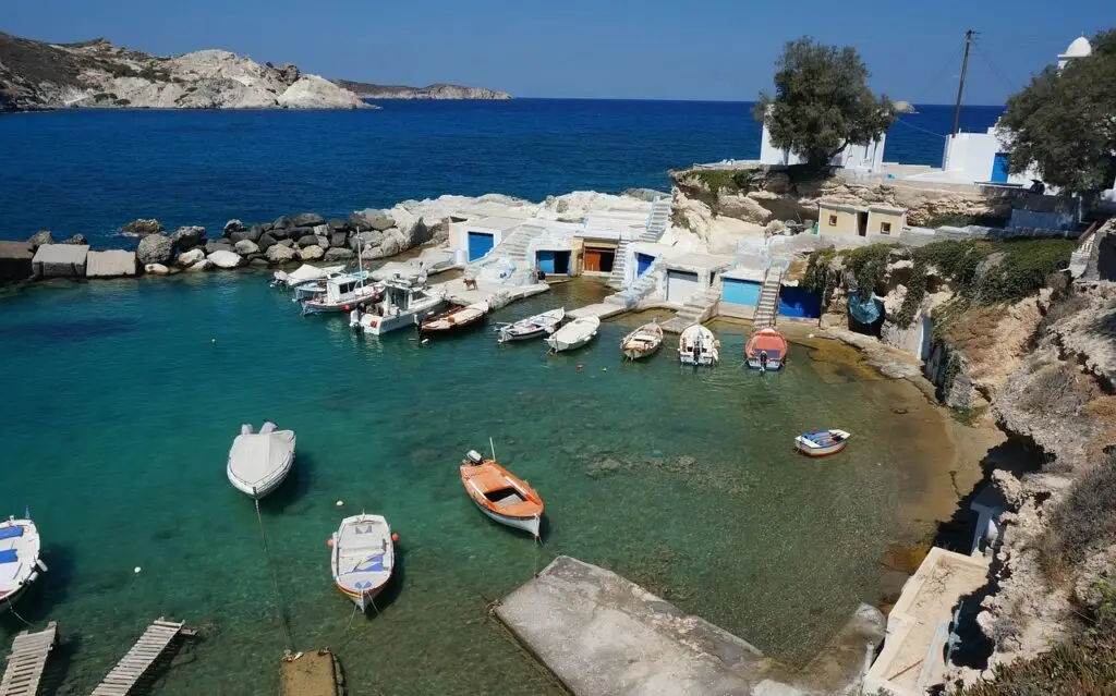 Village de pêcheurs à Milos île grecque avec syrmata colorés et bateaux dans une crique turquoise.